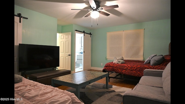 living room with wood-type flooring, a barn door, and ceiling fan