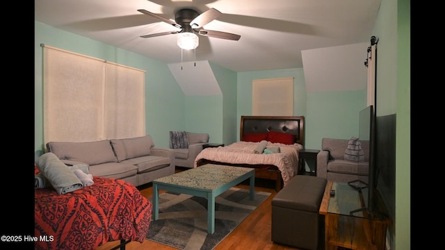 bedroom featuring ceiling fan, wood-type flooring, and a barn door