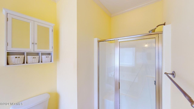 bathroom featuring ornamental molding, a shower with door, and toilet