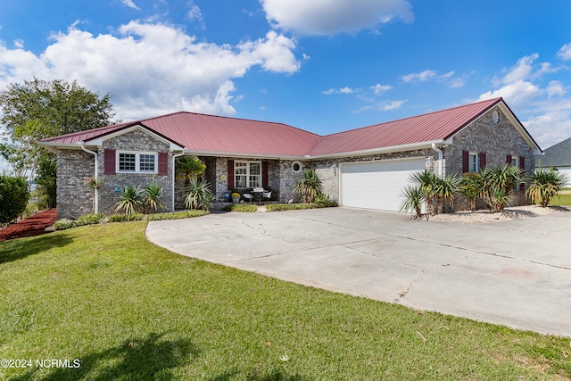 ranch-style house featuring a garage, metal roof, driveway, and a front lawn