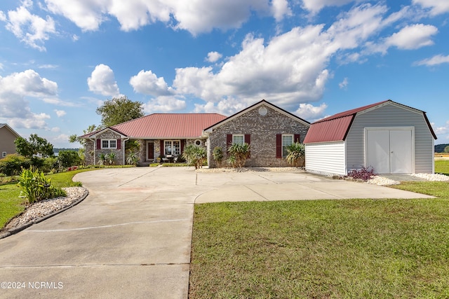 ranch-style house featuring a storage unit, brick siding, an outbuilding, metal roof, and a front lawn