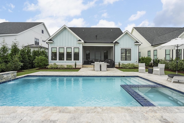 back of property featuring board and batten siding, a pool with connected hot tub, a patio, and fence