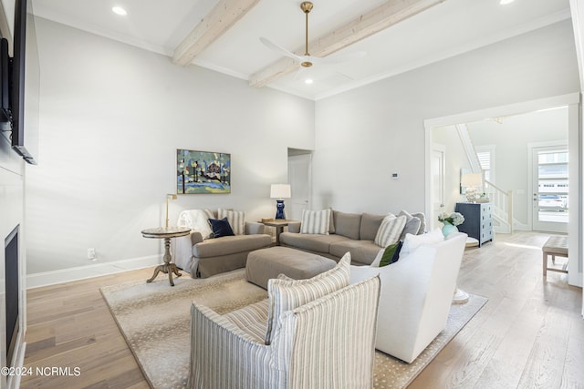 living room featuring crown molding, beam ceiling, ceiling fan, and light hardwood / wood-style flooring