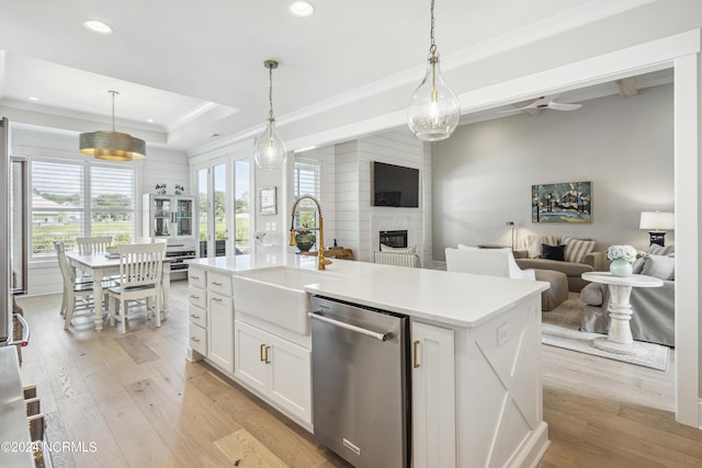 kitchen featuring sink, an island with sink, decorative light fixtures, and stainless steel dishwasher