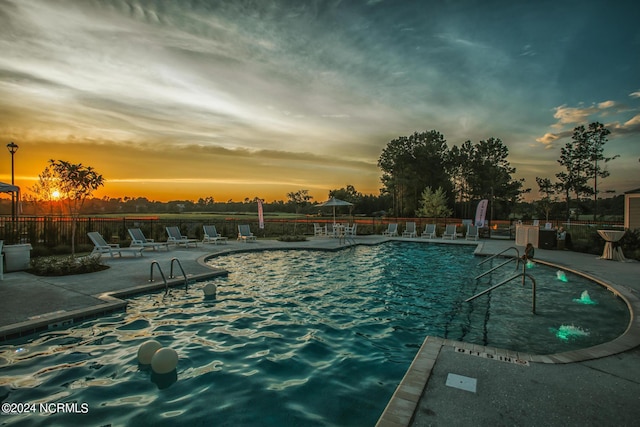 pool at dusk featuring a patio area