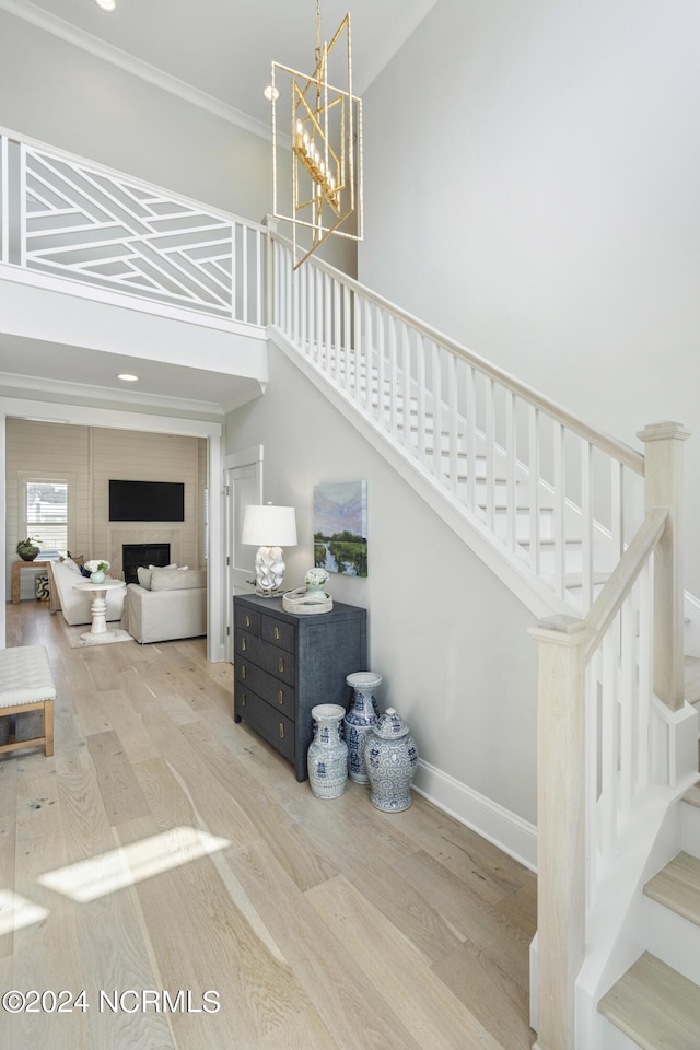 stairway with an inviting chandelier, hardwood / wood-style floors, and ornamental molding