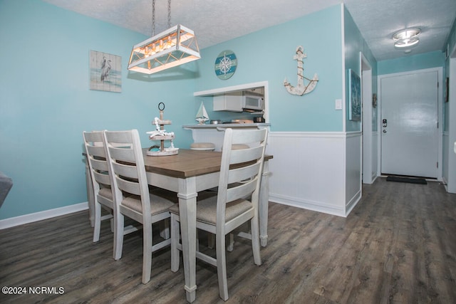 dining room with a textured ceiling and dark wood-type flooring