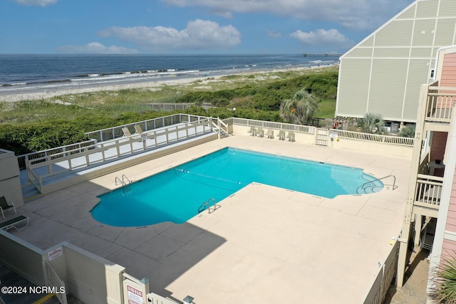 view of pool featuring a water view, a beach view, and a patio area