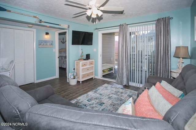 living room with ceiling fan, a textured ceiling, and dark wood-type flooring