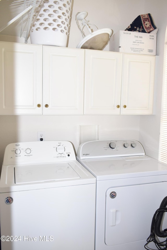 clothes washing area featuring cabinets and washing machine and clothes dryer