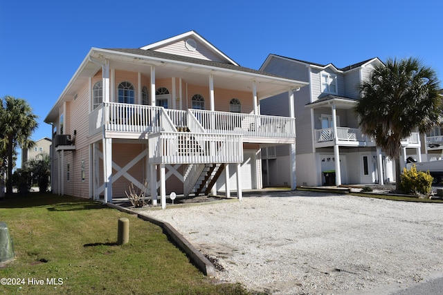 coastal home with a porch, a front yard, and a garage