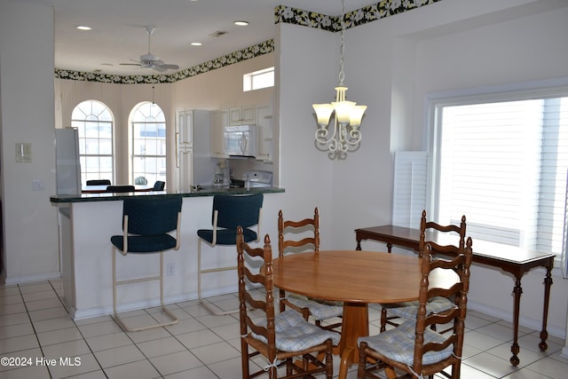 dining space featuring light tile patterned floors and ceiling fan with notable chandelier