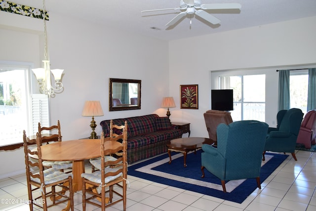 tiled living room with ceiling fan with notable chandelier