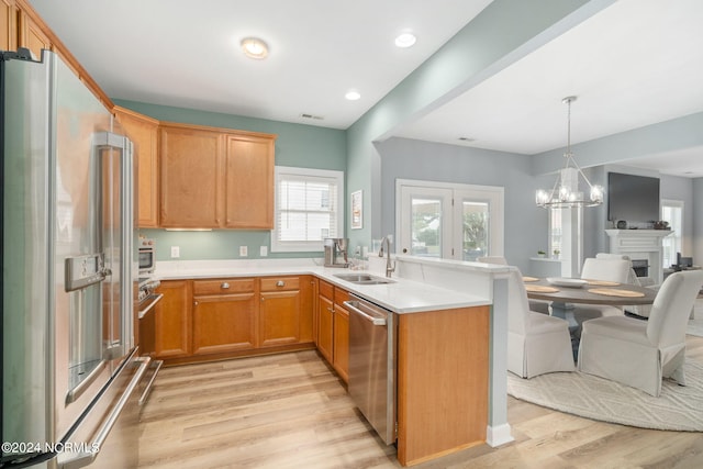 kitchen featuring appliances with stainless steel finishes, light wood-type flooring, sink, and a chandelier