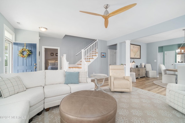 living room with ceiling fan with notable chandelier and hardwood / wood-style flooring