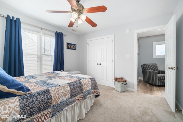 bedroom featuring multiple windows, light carpet, ceiling fan, and a closet