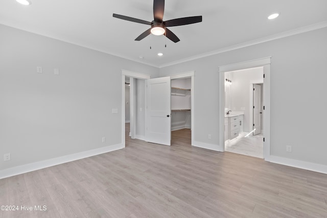 unfurnished bedroom with ceiling fan, ensuite bathroom, light hardwood / wood-style floors, a walk in closet, and ornamental molding