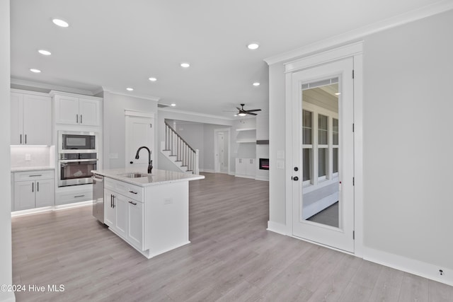 kitchen featuring white cabinets, appliances with stainless steel finishes, a center island with sink, and sink