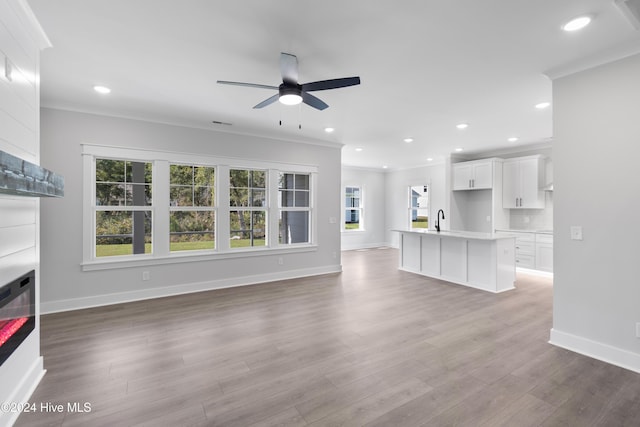 unfurnished living room featuring hardwood / wood-style floors, ceiling fan, ornamental molding, and sink