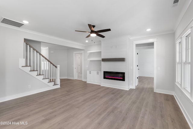 unfurnished living room with a large fireplace, ceiling fan, light hardwood / wood-style flooring, and ornamental molding