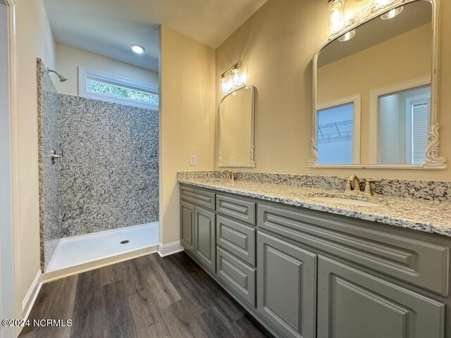 bathroom with a tile shower, hardwood / wood-style flooring, and vanity