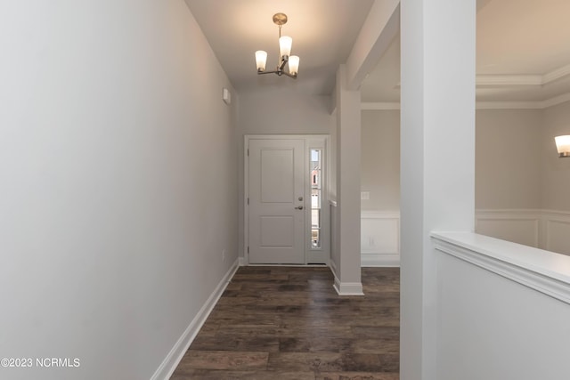 foyer entrance featuring ornamental molding, an inviting chandelier, and dark wood-type flooring