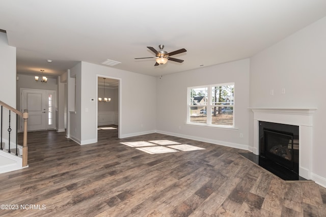 unfurnished living room with ceiling fan with notable chandelier and dark hardwood / wood-style flooring