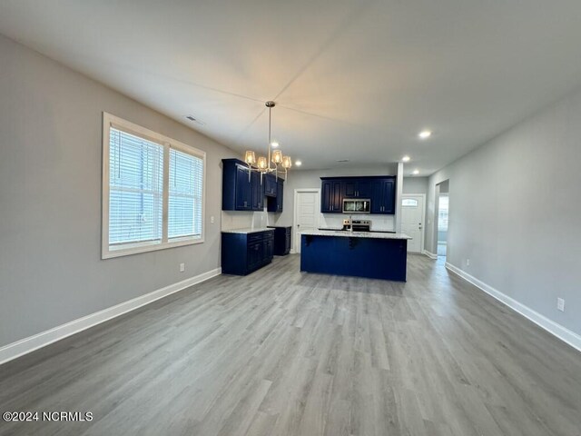 unfurnished living room featuring wood-type flooring and an inviting chandelier