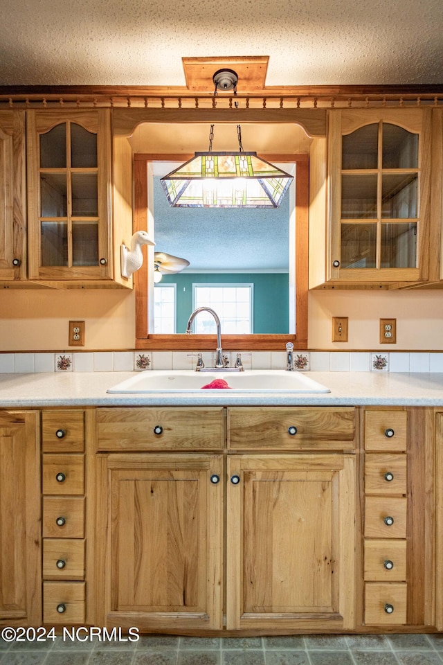 kitchen with a textured ceiling, sink, and hanging light fixtures