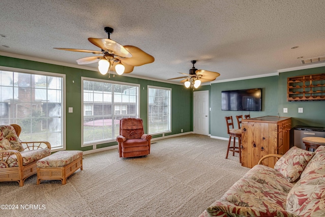 living room with ceiling fan, a textured ceiling, ornamental molding, and light colored carpet