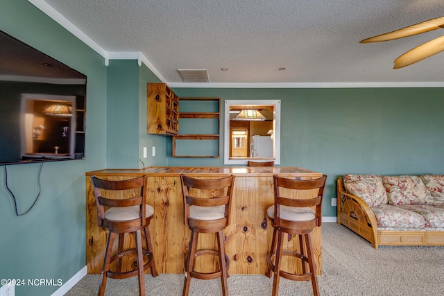 interior space featuring a textured ceiling, crown molding, white fridge, and light colored carpet