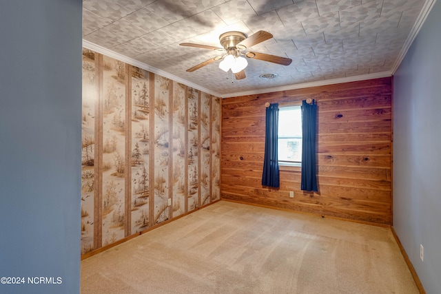 empty room featuring wood walls, crown molding, carpet, and ceiling fan