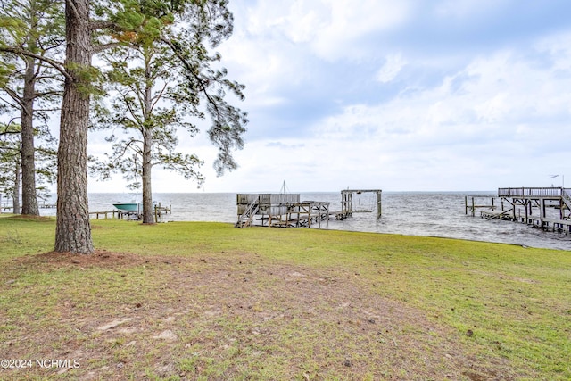 view of dock with a lawn and a water view