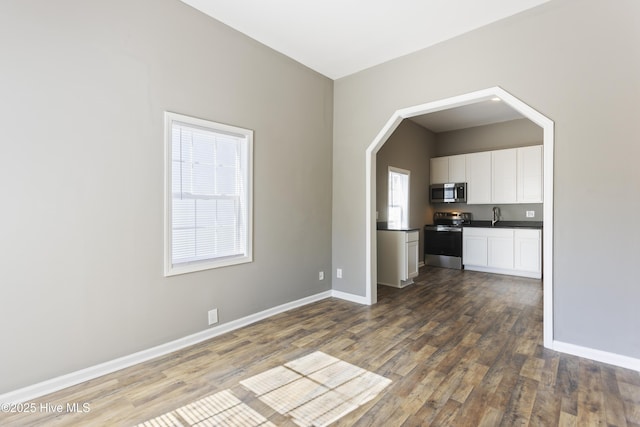 interior space with stainless steel appliances, sink, white cabinets, and dark hardwood / wood-style flooring