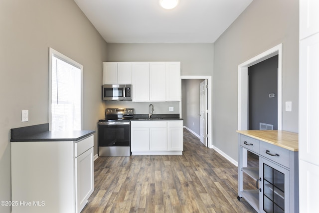 kitchen featuring sink, dark wood-type flooring, stainless steel appliances, and white cabinets