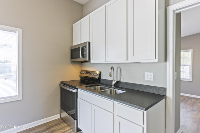 kitchen with stainless steel appliances, sink, dark wood-type flooring, and white cabinets