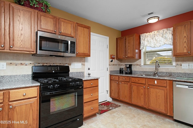 kitchen with brown cabinetry, visible vents, appliances with stainless steel finishes, and a sink