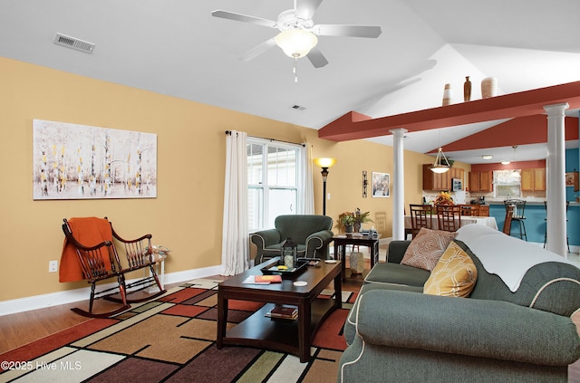 living room featuring visible vents, lofted ceiling, light wood-style flooring, and ornate columns