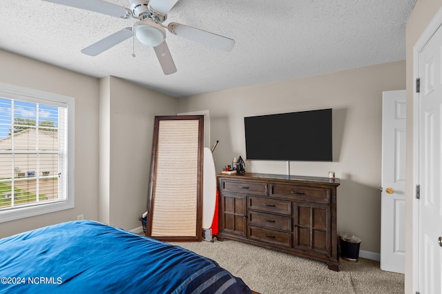 bedroom featuring light carpet, ceiling fan, and a textured ceiling