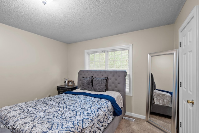 bedroom with a textured ceiling and light colored carpet