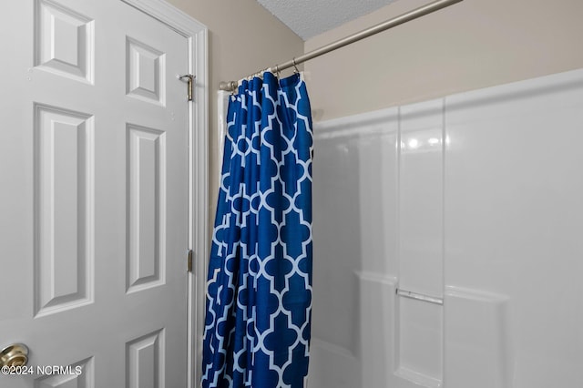 bathroom with a textured ceiling and a shower with shower curtain