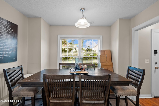 dining space featuring wood-type flooring and a textured ceiling