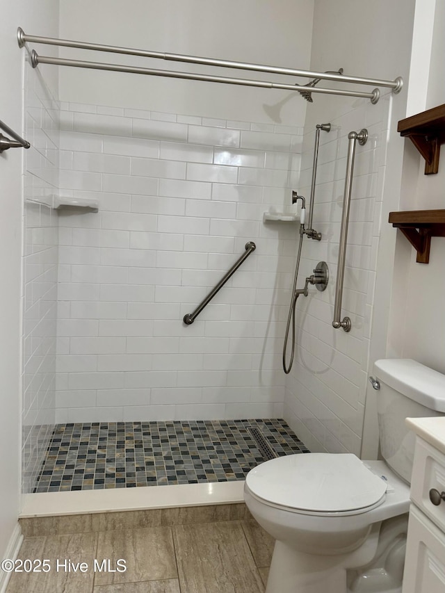 bathroom featuring vanity, toilet, and tiled shower