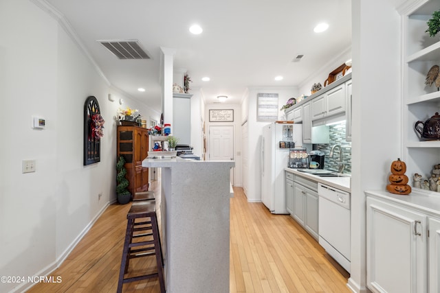 kitchen with sink, crown molding, a breakfast bar, dishwasher, and light wood-type flooring