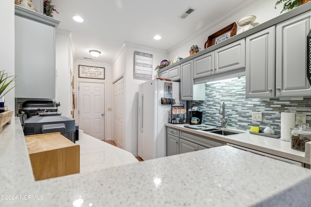 kitchen with gray cabinets, tasteful backsplash, sink, white refrigerator, and crown molding