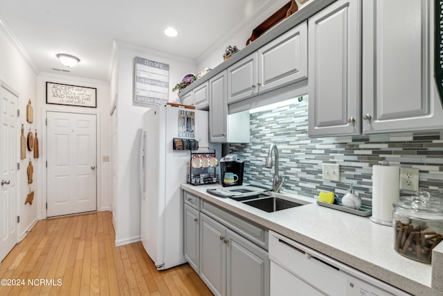 kitchen with sink, crown molding, light hardwood / wood-style flooring, white appliances, and backsplash