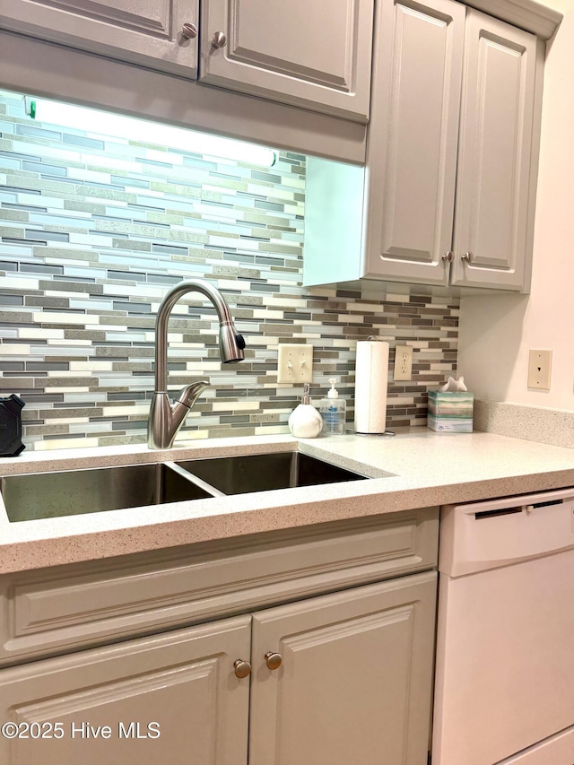 kitchen with white dishwasher, sink, and tasteful backsplash