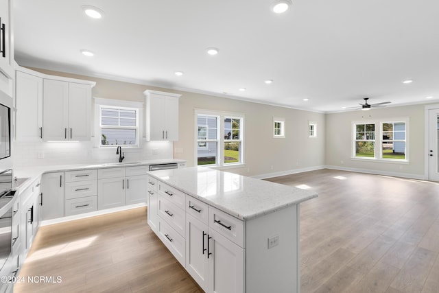 kitchen with a kitchen island, ceiling fan, white cabinets, decorative backsplash, and light hardwood / wood-style flooring