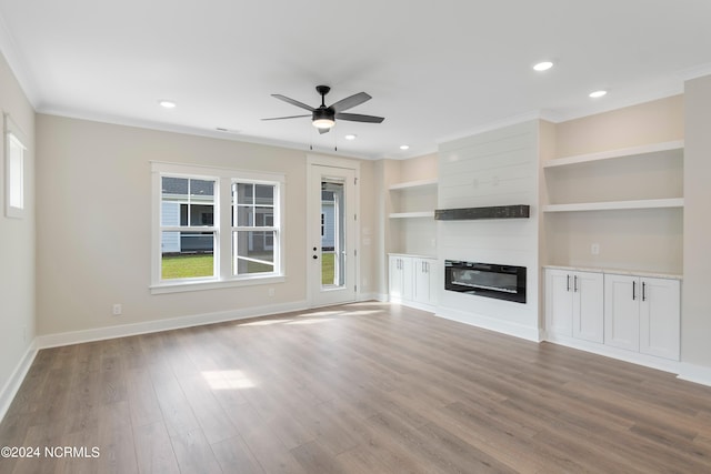 unfurnished living room with ornamental molding, built in shelves, a fireplace, light hardwood / wood-style floors, and ceiling fan