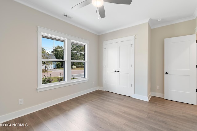 unfurnished bedroom with ornamental molding, a closet, light hardwood / wood-style floors, and ceiling fan